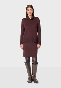 Maglione a maglia color bordeaux con collo a spirale, orlo a coste, abbinato a una gonna coordinata lunga fino al ginocchio e stivali marroni alti fino al ginocchio.