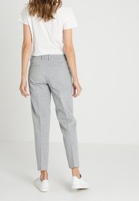 Pantaloni grigi su misura realizzati in un materiale morbido, con una vestibilità dritta e tasche posteriori, abbinati a sneakers bianche.