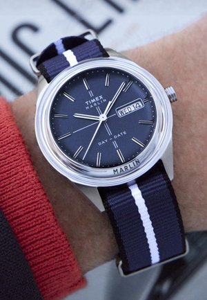 Orologio Timex Marlin con cassa in acciaio inox, quadrante blu navy, datario e cinturino in nylon a righe blu navy con accenti bianchi.