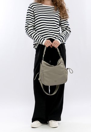 Šedá taška přes rameno z měkkého materiálu s pleteným držadlem, s hladkou texturou a nenápadným logem na přední straně. Pruhované tričko s dlouhým rukávem.