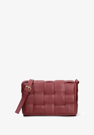 Small rectangular burgundy leather crossbody bag with wide woven straps and adjustable buckle strap on white background.