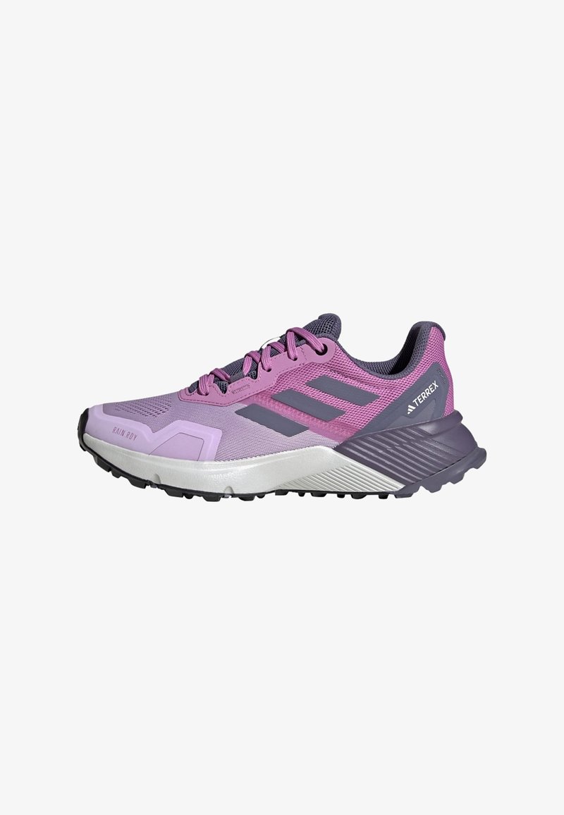 Chaussure de trail Adidas Terrex violette et grise avec semelle noire, dessus en mesh et fermeture à lacets, vue de côté sur fond blanc.