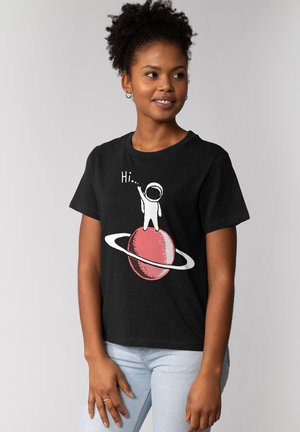 Zwart t-shirt met een afbeelding van een astronaut op een roze planeet met ringen, en de tekst "Hi..." in het wit erboven.