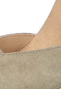 Zapato de ante verde con una superficie texturizada, que presenta un diseño de corte en V y un forro interior marrón claro.