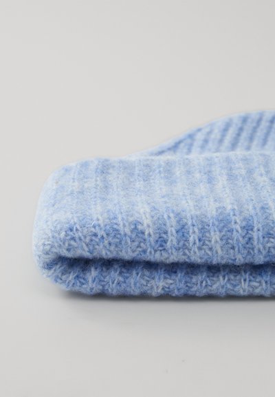 Cappello di lana blu chiaro morbido e piegato, realizzato a maglia con una texture a coste, su uno sfondo chiaro e semplice.
