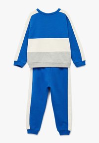 Blå og hvid hyggelig sweatshirt og sweatpants sæt. Har horisontale farveblokke: kongeblå, hvid og lys grå. Blødt, strækbart stof.