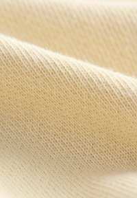 Tessuto a maglia beige chiaro con una trama liscia, caratterizzato da una tessitura densa e uniforme e leggere variazioni di tonalità.