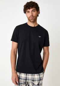 Black cotton t-shirt with a crew neckline and short sleeves. Features a small white embroidered logo on the chest. Plain design.