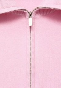 Pull à fermeture éclair rose clair avec un col côtelé et une fermeture éclair argentée au centre, en tissu doux et texturé.