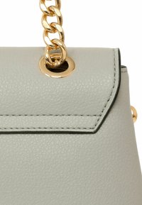 Borsa a tracolla in pelle grigia con texture, dotata di una tracolla a catena dorata, una asola metallica dorata e cuciture lungo il bordo della patta.