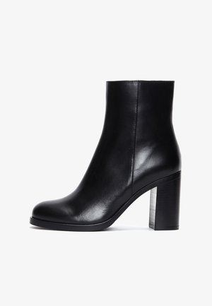 Zwarte leren enkellaars met een ronde neus, een gladde textuur en een dikke blokhak. Stijlvol ontwerp met minimalistische details.