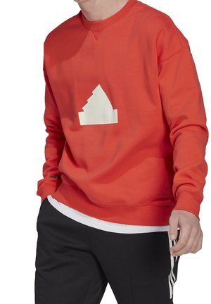 Sudadera roja hecha de una tela suave, con un gráfico triangular blanco en la parte frontal. Mangas largas y diseño de cuello redondo.