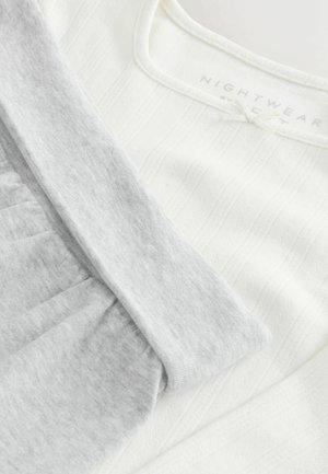 Vit nattklädesmaterial med ribbad textur, kombinerat med mjukt grått tyg. Har rund halsringning och samlade detaljer. Etikett synlig.