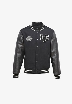 Chaqueta de varsity negra con cuerpo de lana y mangas de cuero, con letras blancas "LTC" y un parche circular en el pecho, puños de canalé a rayas.