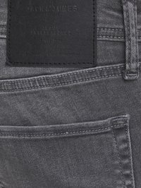 Sive traperice s teksturiranim finišem, s crnom kožnom naljepnicom na stražnjem dijelu struka s natpisom "Jack & Jones" i klasičnim detaljima šivanja.
