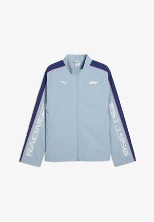 Chaqueta Puma azul claro con mangas azul marino, ribete rosa, "RACING" en la manga izquierda, "EST. 1950" en la manga derecha y logotipo de F1 en el pecho.