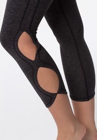 Leggings de sport noirs avec découpes en mesh, tissu texturé et coutures contrastantes, dotés d'une coupe ajustée et d'une longueur raccourcie.