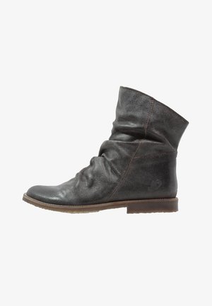 Botín tobillo desgarbado hecho de cuero gris con un acabado ligeramente desgastado, presenta una suela marrón baja y plana, además de detalles de costura sutiles.