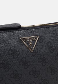 Black handbag with textured synthetic material. Features a gold-tone triangular logo and gold zipper. Subtle embossed pattern throughout.