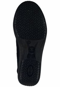 Semelle de chaussure noire avec un motif de semelle texturé. Présente un marquage circulaire et des indications de taille, fabriquée en matériau durable similaire au caoutchouc.