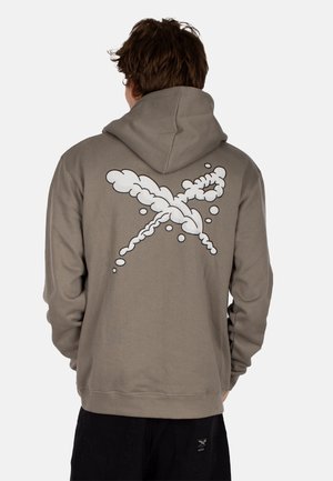 Felpa marrone con un ampio design grafico bianco che assomiglia a nuvole sulla schiena. Realizzata in tessuto morbido, con una vestibilità comoda e una tasca a canguro.