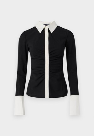 Crna košulja dugih rukava s bijelim ovratnikom i plaketom. Ima nabranu prednju stranu i kontrastne bijele manšete, izrađena od glatkog materijala.