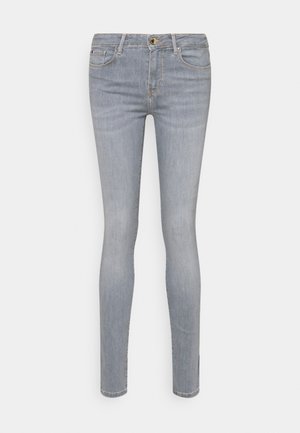 Jeans ajustados en denim gris claro. Presentan un cierre con cremallera y botón, diseño de cinco bolsillos, y un desvanecimiento sutil con una textura suave.