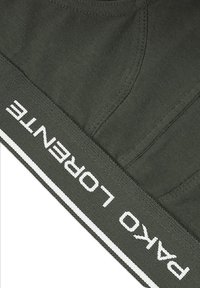 Oliwkowe bawełniane szorty z elastycznym pasem; logo "PAKO LORENTE" w kolorze białym, otoczone białą lamówką na pasie.