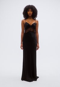 Μαύρο σατέν φόρεμα με κορσέ από δαντέλα, ρυθμιζόμενους λεπτούς ιμάντες και εφαρμοστή σιλουέτα που ρέει μέχρι το πάτωμα, με απαλή υφή και κομψό πέπλο.