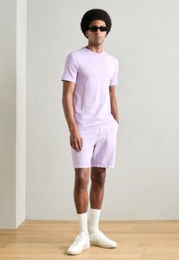 Lavendel bomull t-skjorte og matchende shorts med en avslappet passform. Hvite sneakers og ankelsokker fullfører antrekket.