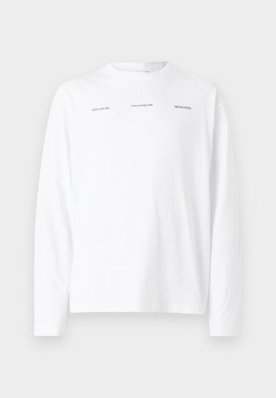 T-shirt bianco a maniche lunghe in cotone. Presenta tre testi stampati: "HZW (25-26)", "HOLZWEILER" e "MEMORIES" in font nero.