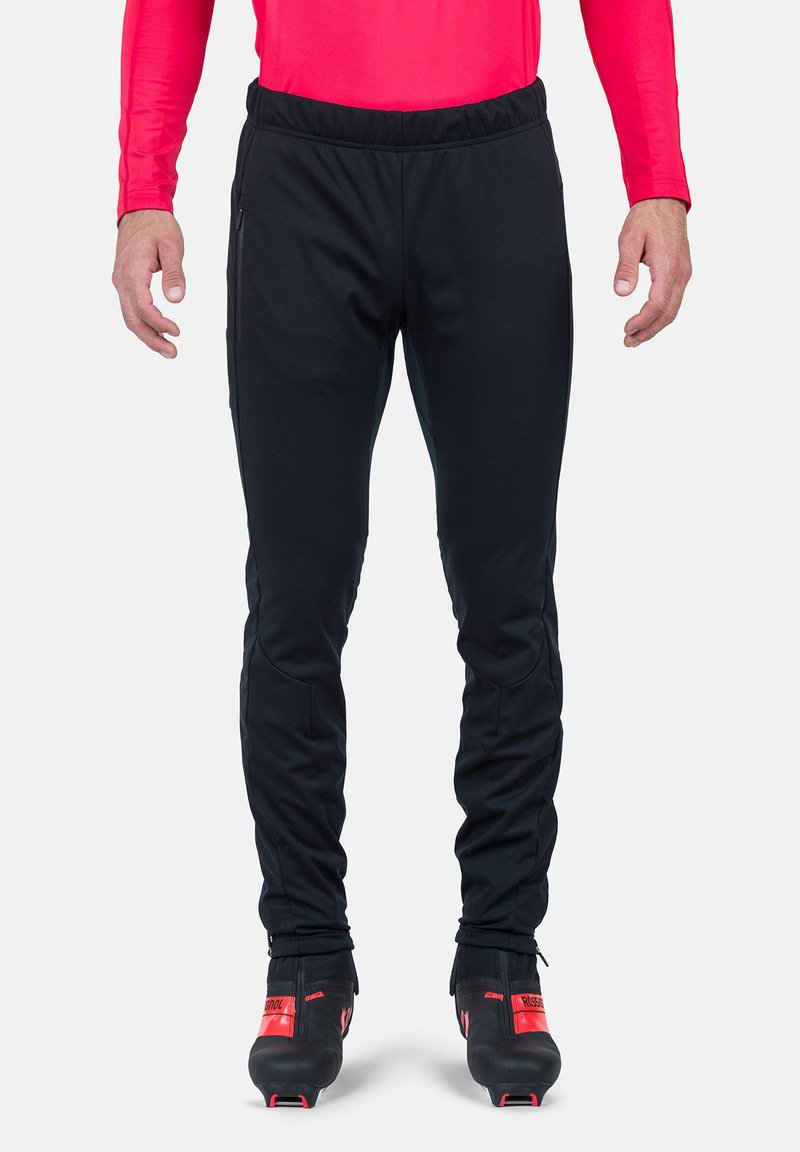 Schwarze Sporthose mit schmalem Schnitt, elastischem Bund, seitlichen Reißverschlusstaschen und kontrastierenden Reißverschlussdetails an den Knöcheln.