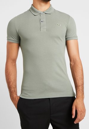 Grünes Polohemd mit kurzen Ärmeln und Kragen, ausgestattet mit einer Knopfleiste mit drei Knöpfen und einem kleinen, aufgestickten Logo auf der linken Brust. Strukturierter Stoff.