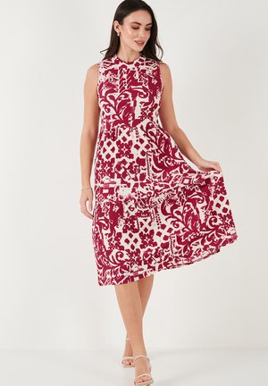 A sleeveless, knee-length dress featuring a floral and geometric burgundy and white pattern, with a fitted bodice and flowing skirt.