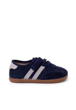 Marineblå børnesneaker med beige striber, velcrolukning og brun gummisål, vist fra ydersiden.