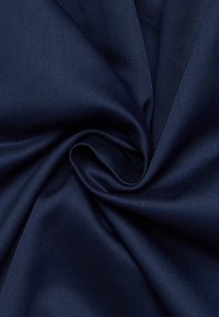 Tessuto blu navy con una texture liscia e morbida; presenta una leggera lucentezza e un fine motivo a costine diagonali. Tagliato in una forma spirale.