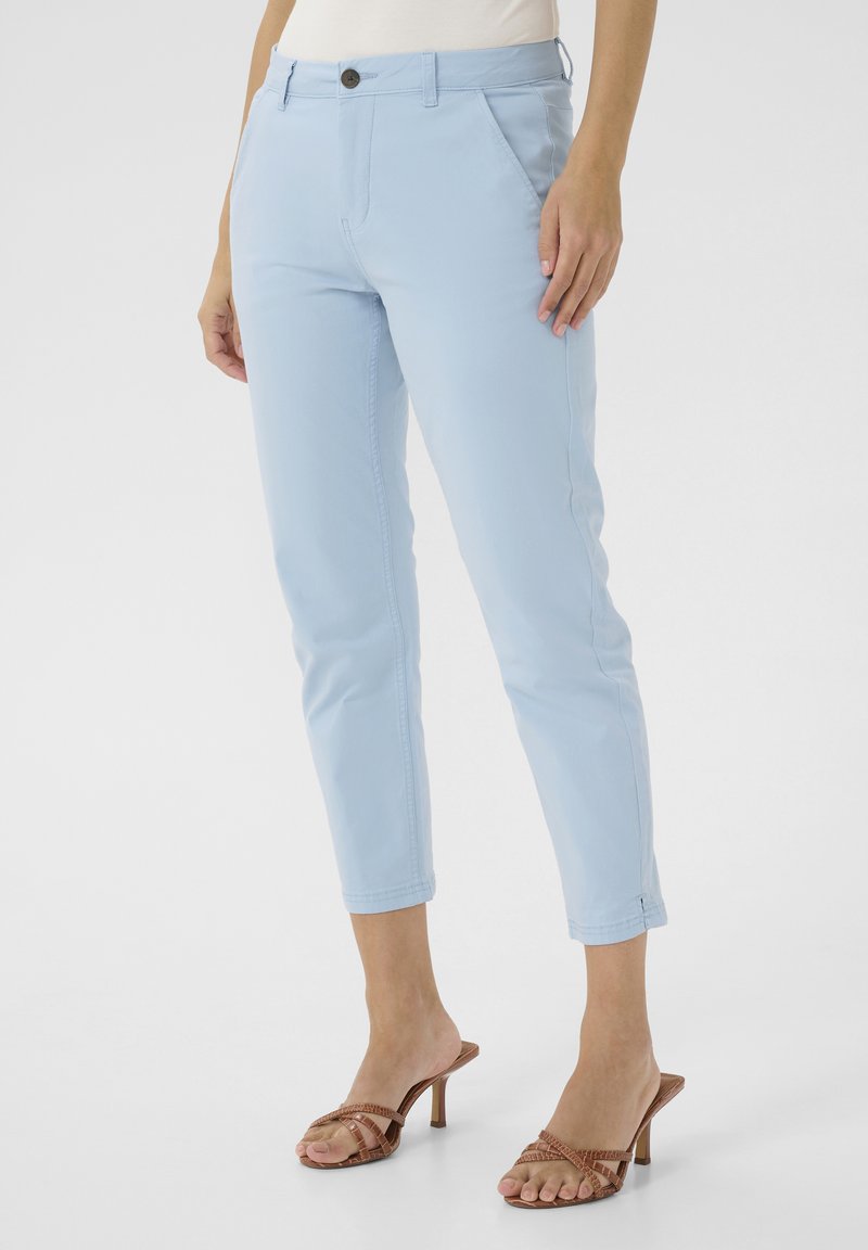 Svijetloplave hlače od pamuka s mješavinom, uskog kroja, s kopčanjem na gumb, prednjim džepovima i završenim rubovima, uparenim s smeškim sandalama na visoku petu.