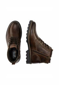 Braune Lederstiefeletten mit Schnürung vorne und seitlichem Reißverschluss. Dicke Gummisohle mit strukturiertem Profil, genähte Akzente entlang der Kante.