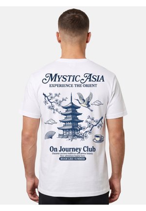 Man wearing white T-shirt with blue pagoda, crane, cherry blossoms, fan, and cup designs and travel-themed text on the back.