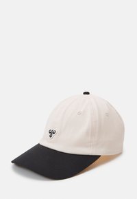 Baseball cap with a soft cream fabric body, black brim, and small embroidered design on the front. Features metal eyelets.