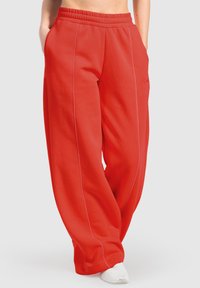 Røde sweatpants med en tekstureret overflade, elastisk talje og to sidelommer. Har kontrasterende lyserød syning og bred ben-design.