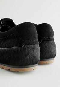 Scarpe nere realizzate in suede e pelliccia, con una texture morbida, retro arrotondato, cuciture a contrasto e una suola in gomma di colore chiaro.