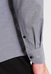 Schwarz-weiße kariert dress shirt, ausgestattet mit einem knöpfbaren Manschette mit einem dezenten Logo und strukturiertem Stoff in einer taillierten Passform.