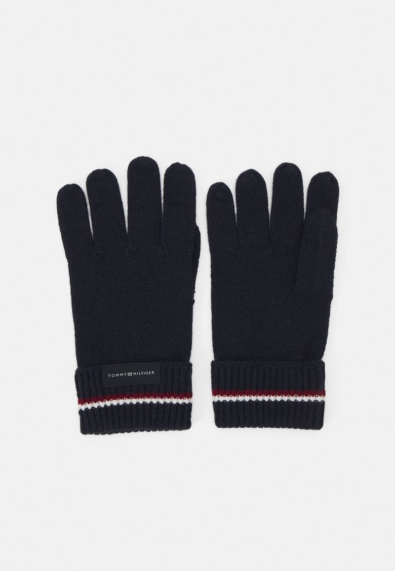 Paire de gants en maille noire avec des rayures rouges, blanches et bleu marine aux poignets, et une petite étiquette rectangulaire sur le poignet du gant gauche.