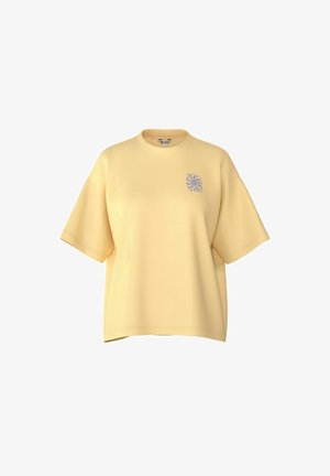 T-shirt ample jaune clair à manches courtes avec un petit motif soleil violet sur la poitrine gauche et un col rond.