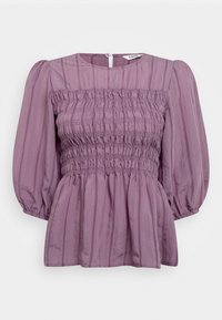 Haut blouse violet avec manches bouffantes, présentant une texture froncée, des rayures verticales et une fermeture boutonnée à l'arrière. Tissu doux et léger.