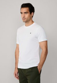 T-shirt bianca a maniche corte in morbido cotone, con un piccolo logo blu navy sul petto e un classico girocollo.