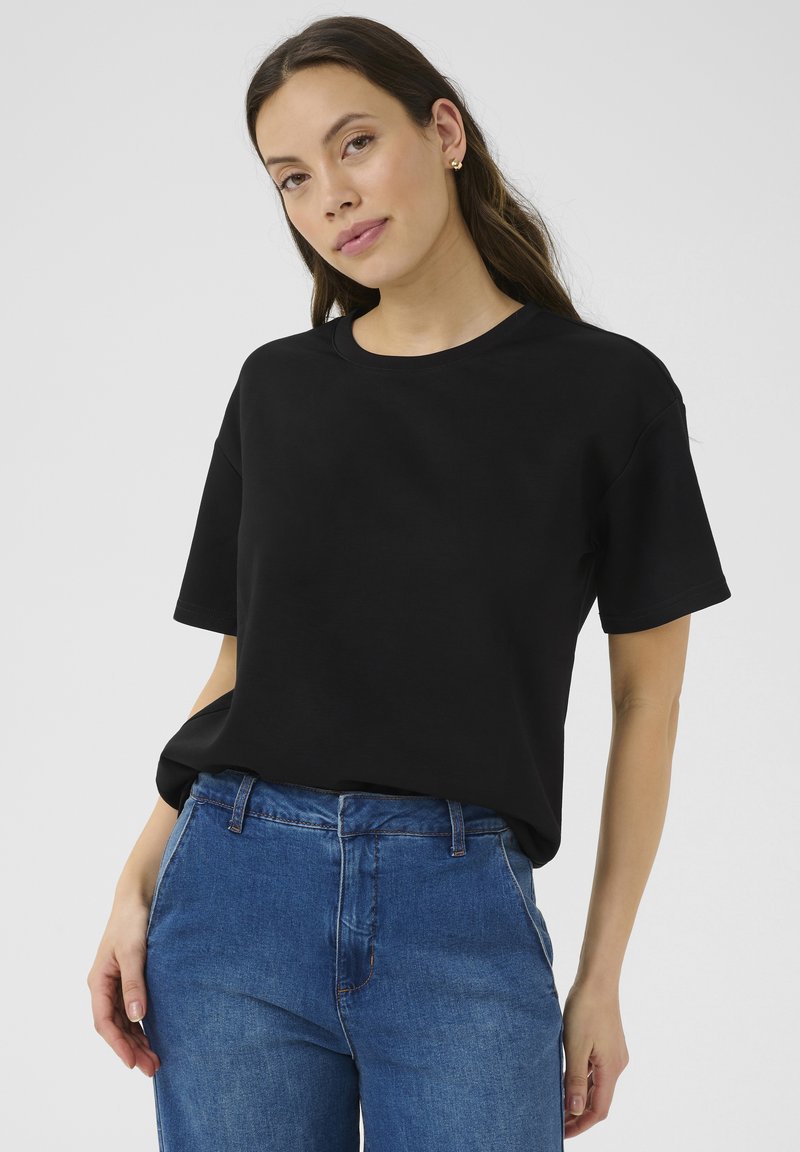 T-shirt nera in cotone, con colletto rotondo e maniche corte. Abbinata a jeans blu per un look informale.