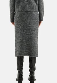 Grauer Strickpullover mit geripptem Saum, figurbetontem Rock und kniehohen schwarzen Lederstiefeln mit glatter Textur und klobigen Absätzen.