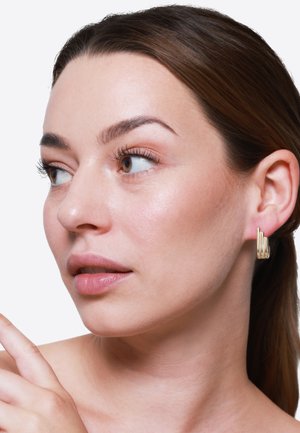 Orecchini oro con un design geometrico caratterizzato da barre verticali. Superfici lisce e lucidate esaltano il look moderno e riflettono la luce.
